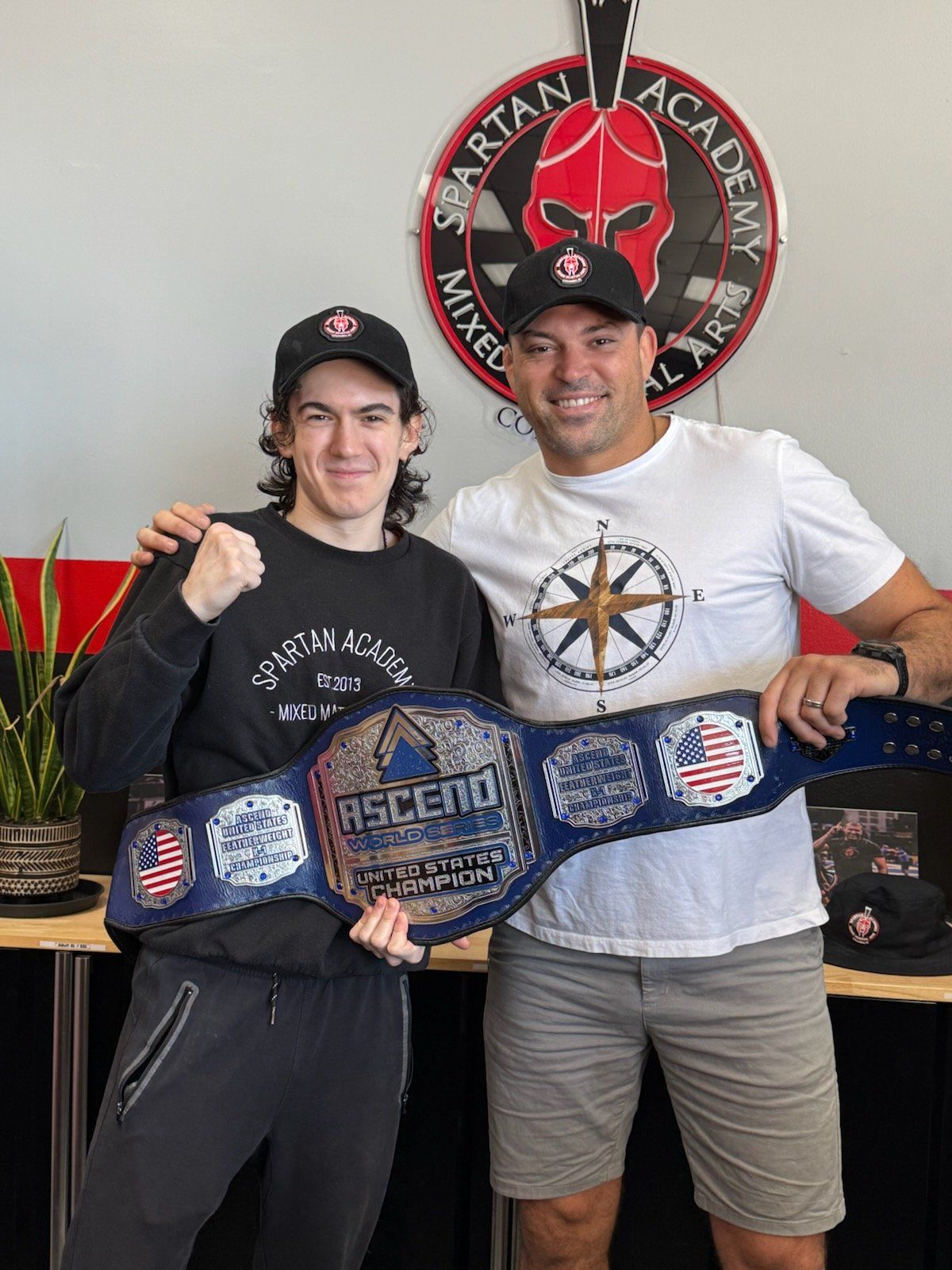 Professor Aidan Stoughton and head professor Guybson Sá holding the Ascend World Series United States Champion belt at Spartan Academy MMA